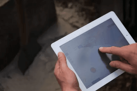 Monteur werkt in DiaFlow op een tablet, staand boven een open sleuf