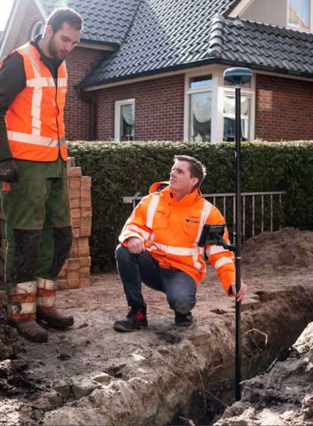 Monteur met tablet en GPS-rover bekijkt de KLIC-melding in het veld